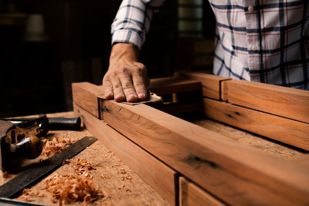 A joiner smoothing the edge of an assembled wooden frame in the workshop