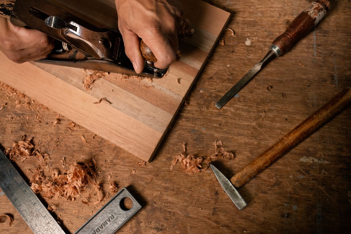 Close-up of a hand plane taking a shaving off a board, curls of wood around it