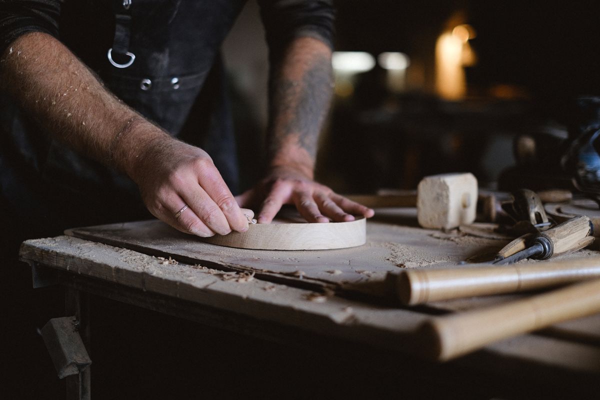 Hands smoothing a turned circular component on the workbench