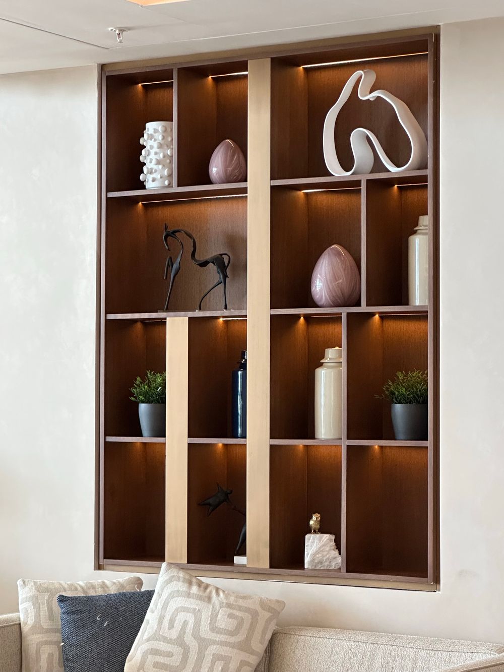 A shelf of ceramics and books against a plaster wall