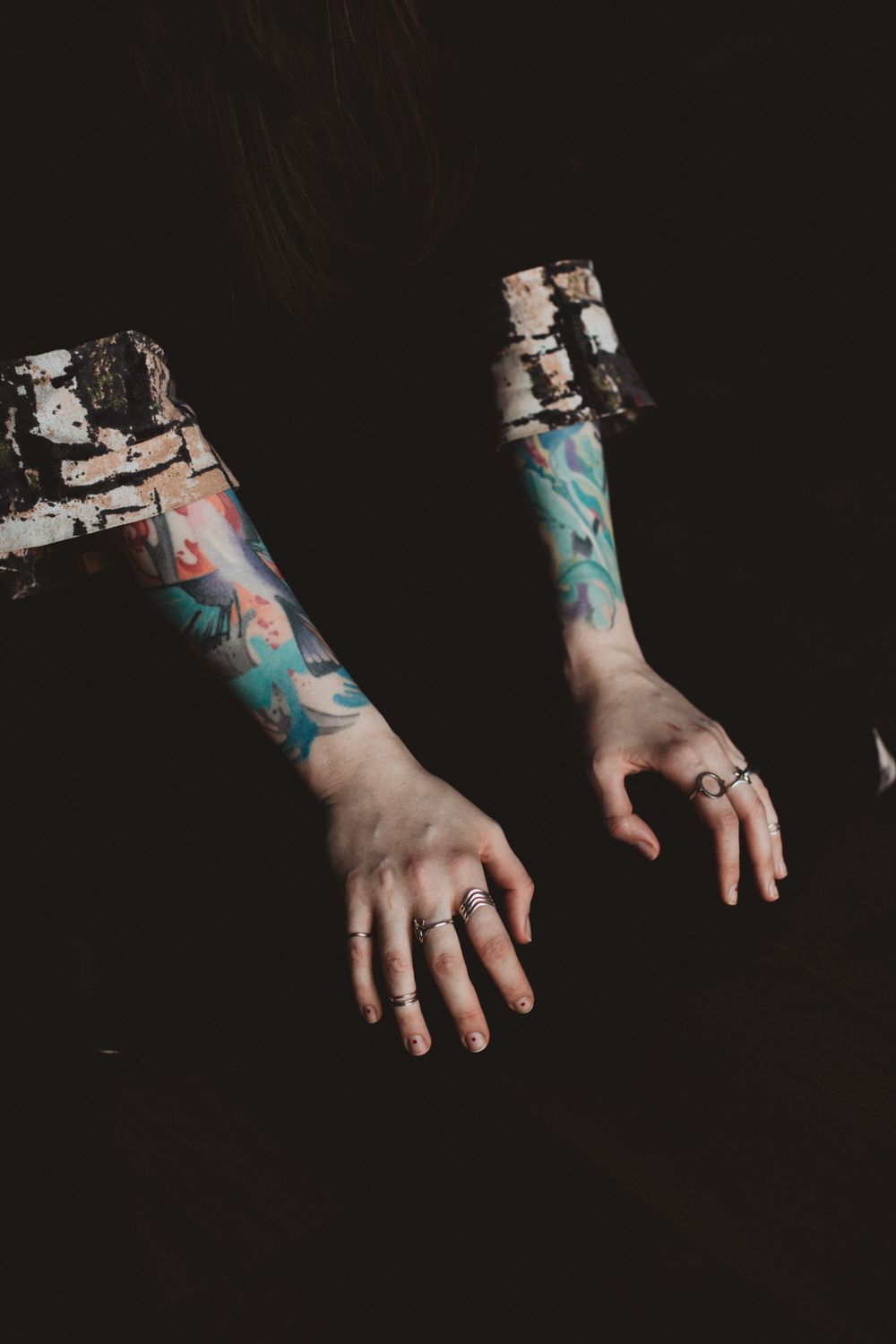 Two colour-sleeved forearms emerging from darkness
