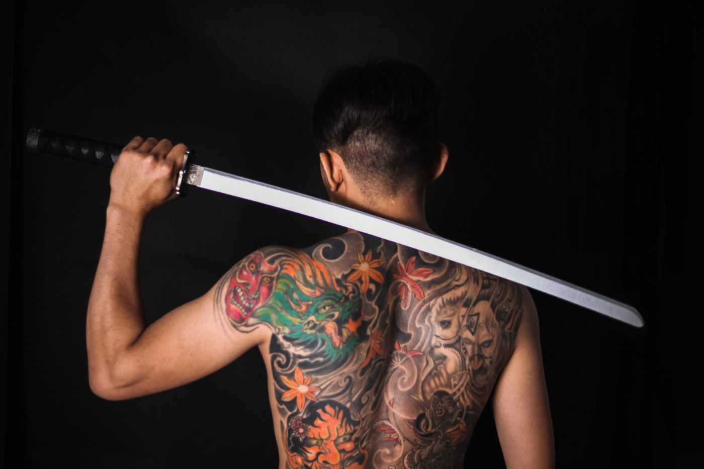 A full Japanese backpiece of a green dragon, maple leaves and chrysanthemums, photographed against black