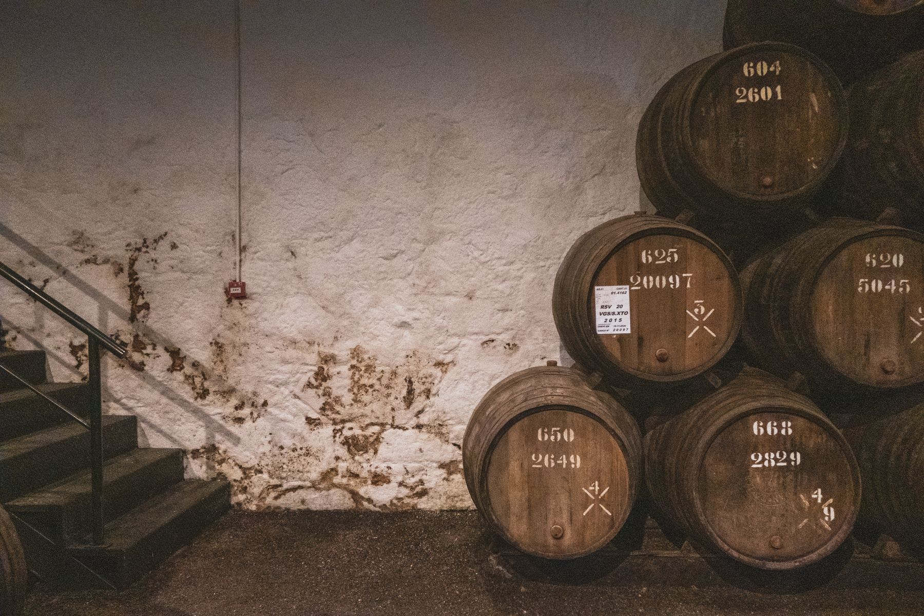Aged oak barrels stacked in a stone-walled rickhouse