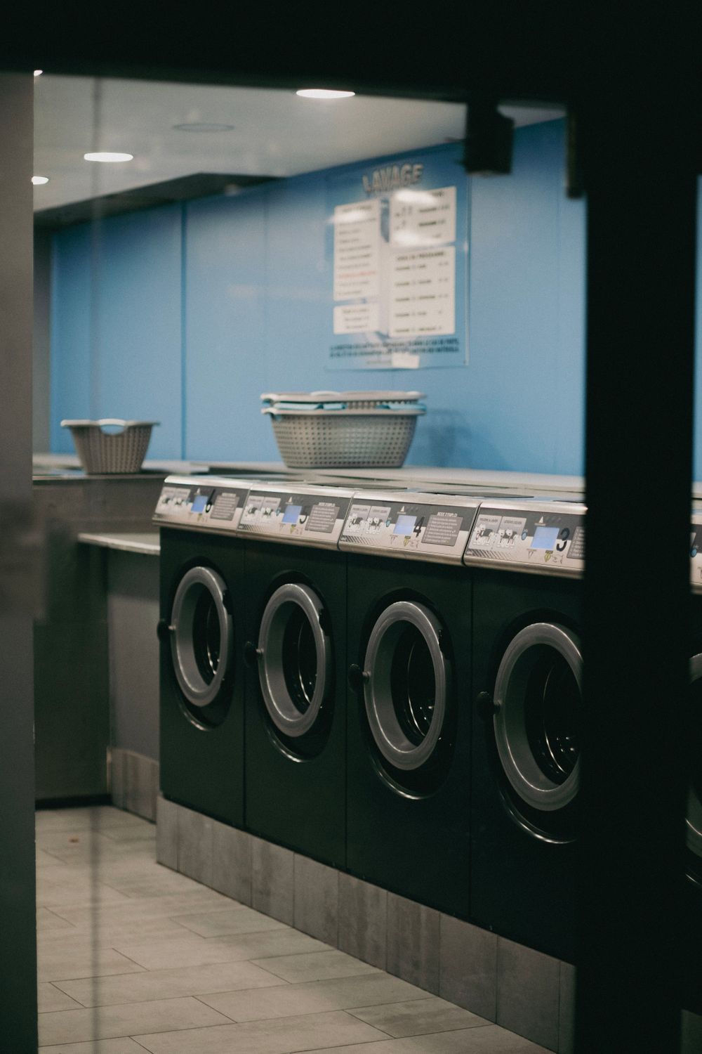 A row of front-loaders along the wall with baskets waiting on the counter above