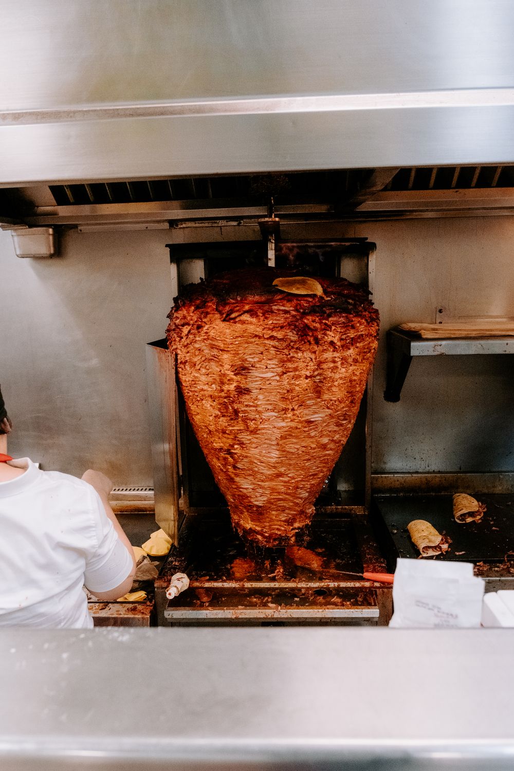 A cook carving from the spinning trompo of marinated pork at the truck's grill