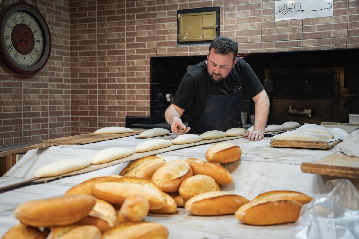 A baker shaping dough on a floured bench