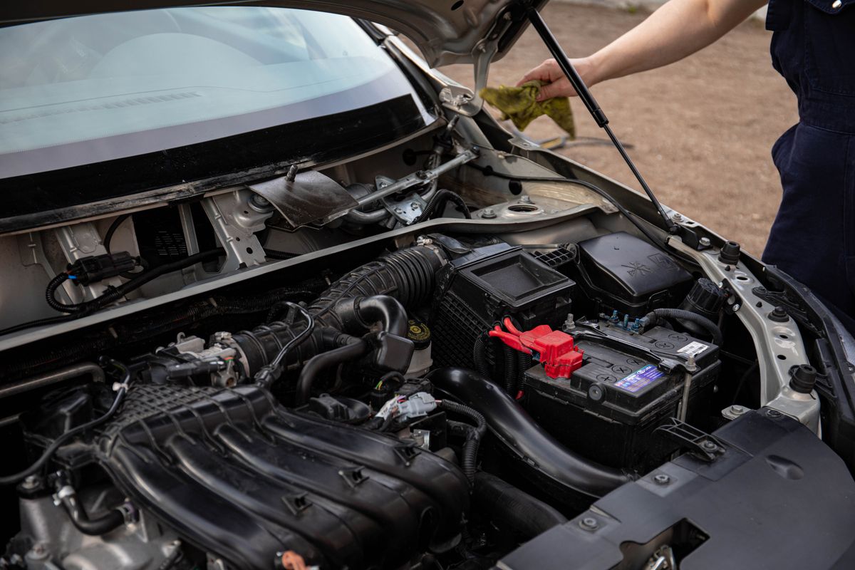 A technician checking the battery and engine bay during a routine service