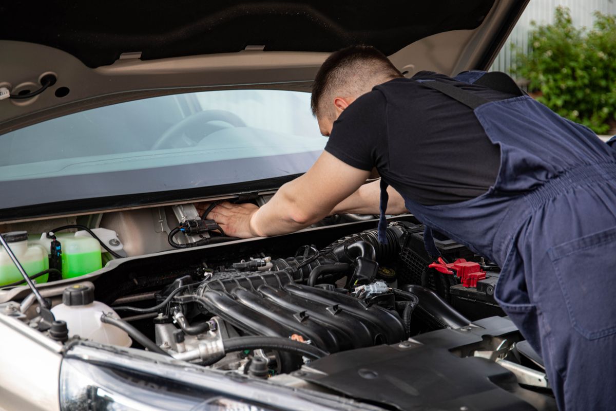 A technician leaning into an open engine bay during a scheduled service