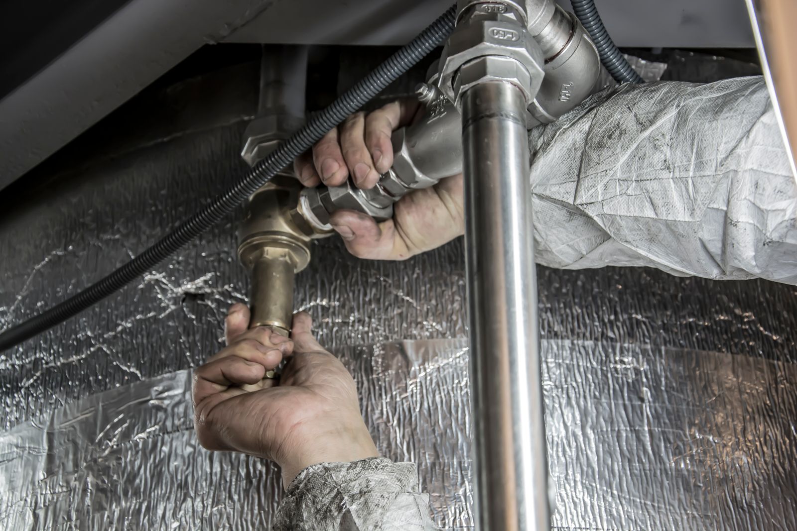 A plumber's hands fitting steel supply pipes