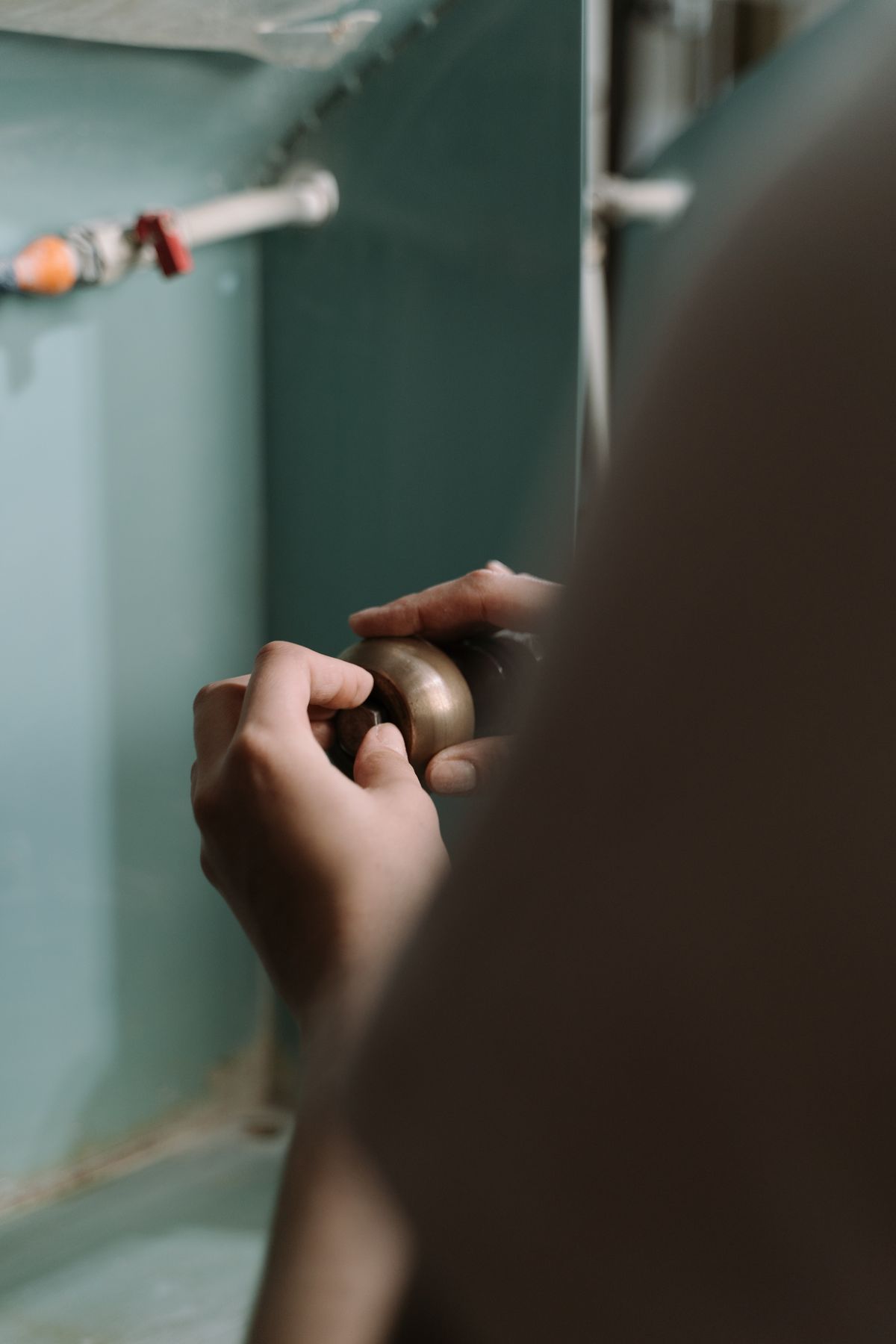 Hands tightening a trap fitting under a kitchen sink