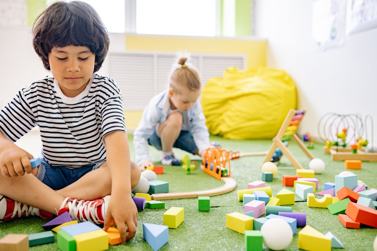 Toddlers building with wooden blocks on a classroom rug