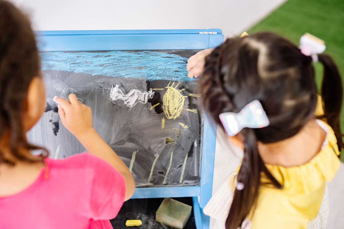 A child drawing with chalk on a classroom blackboard