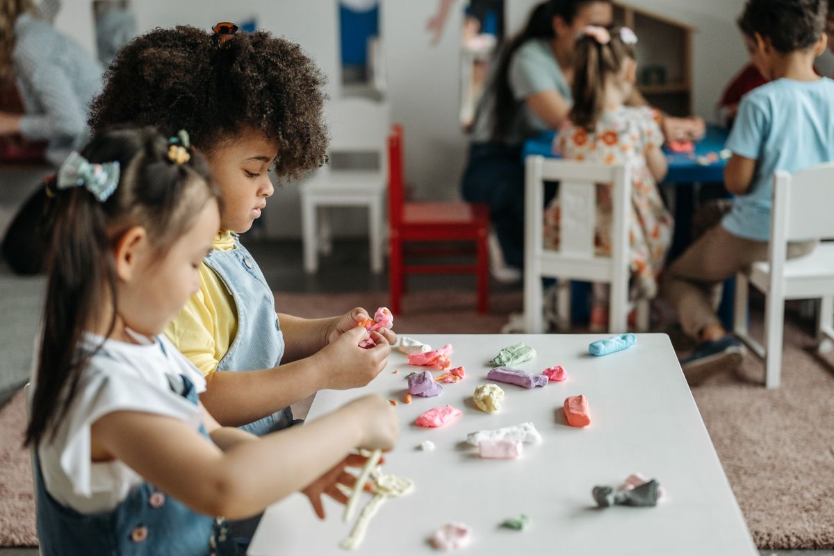 Children rolling coloured modelling clay at a preschool table