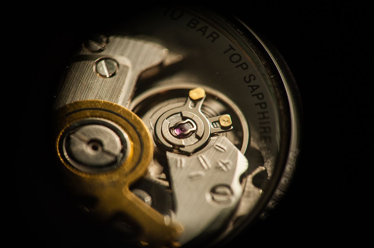 The gear train of an opened movement under bench light, wheels and jewelled bearings in sharp relief
