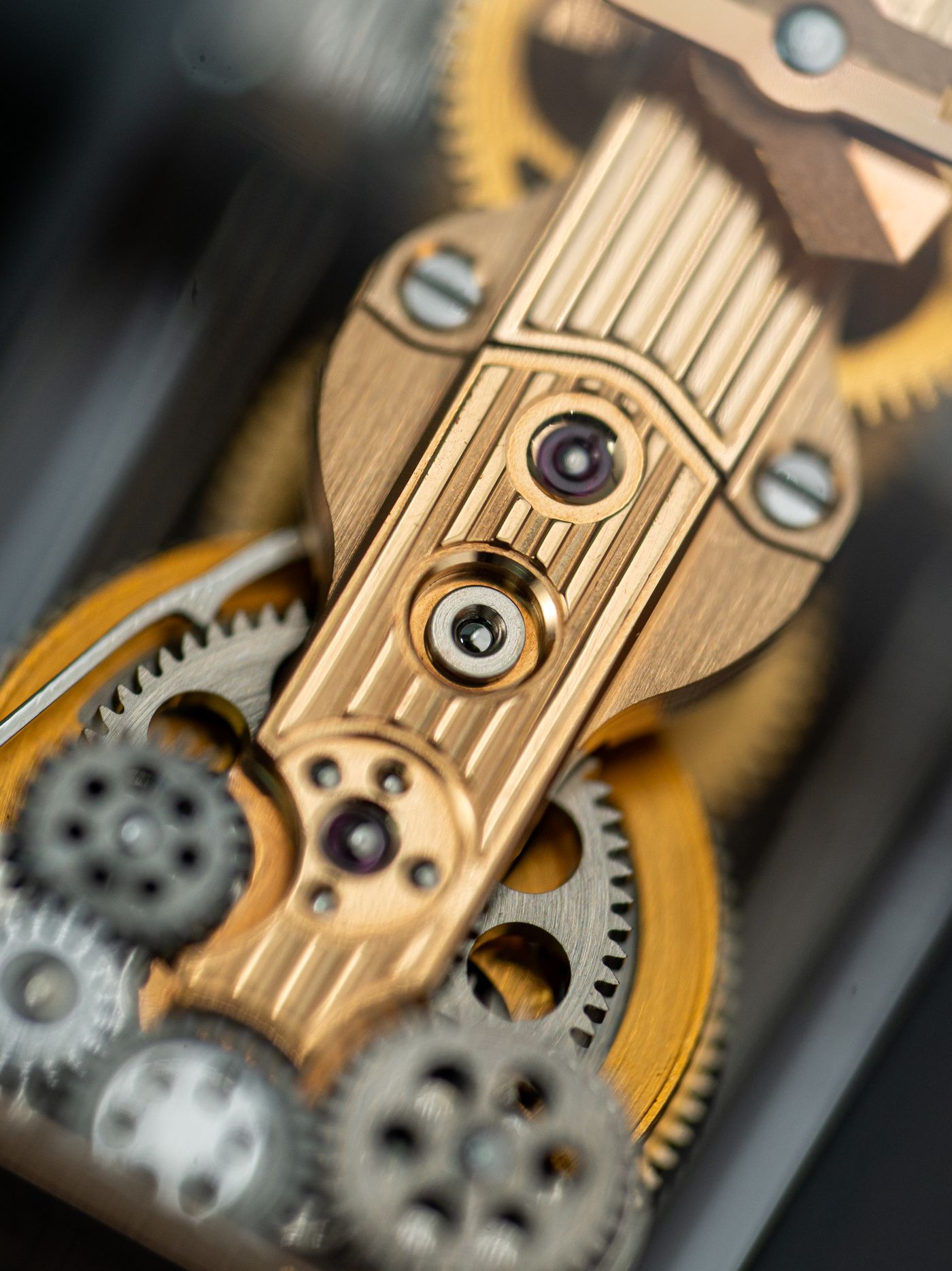 Macro photograph of a gold watch movement, jewelled bearings and gear train in sharp focus