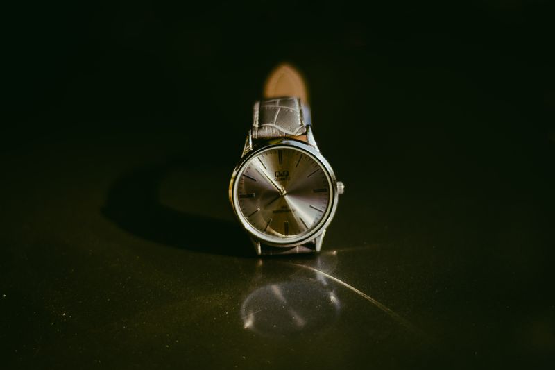 Omega Genève on a dark leather strap, warm silvered dial catching a single light against a black ground