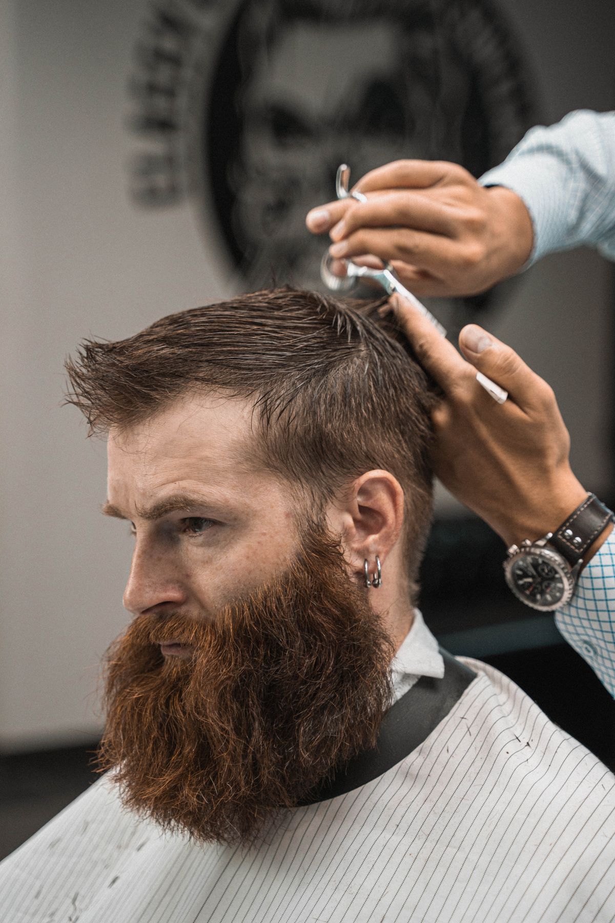 A barber shaping a client's beard with a trimmer