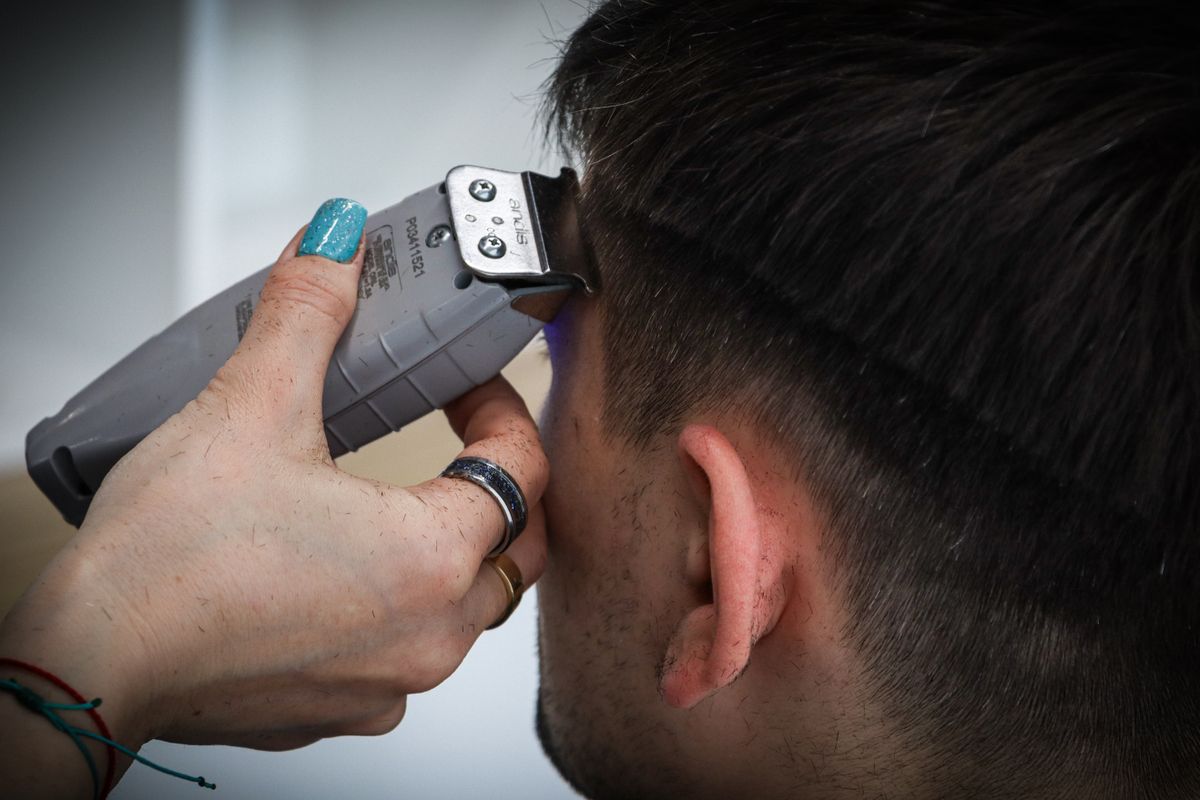 Clippers cutting a tight fade at the back of a client's head