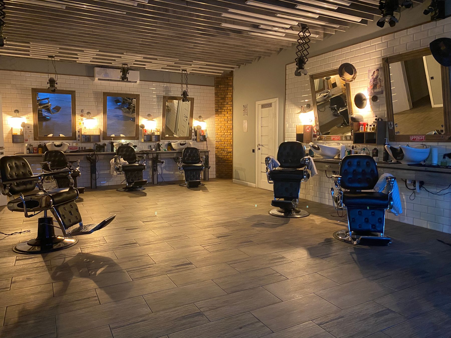 The interior of a barbershop: chairs, mirrors and shelves of tools under warm light