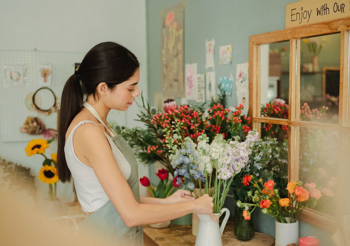 A florist conditioning stems and building an arrangement at the bench