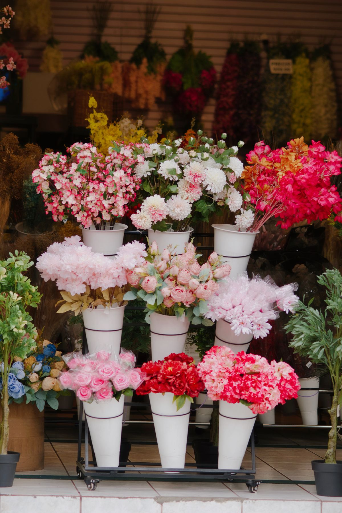 Galvanised buckets of mixed blooms lined up at the shop entrance