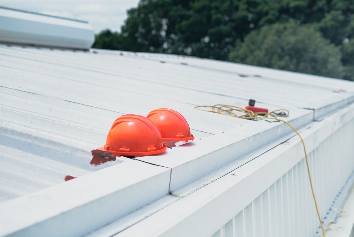 Hard hats and safety harnesses set down on a metal roof deck