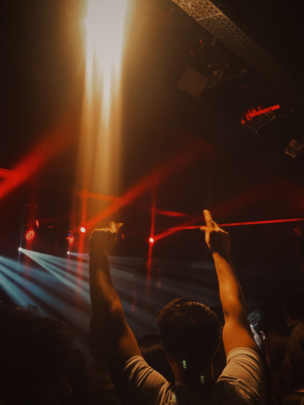Hands raised into crossed red and white beams above the dance floor.