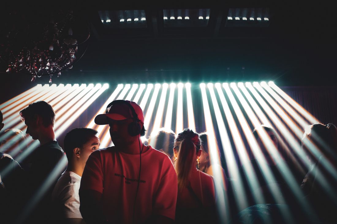 Guests in silhouette against a wall of horizontal light bars on the main floor.