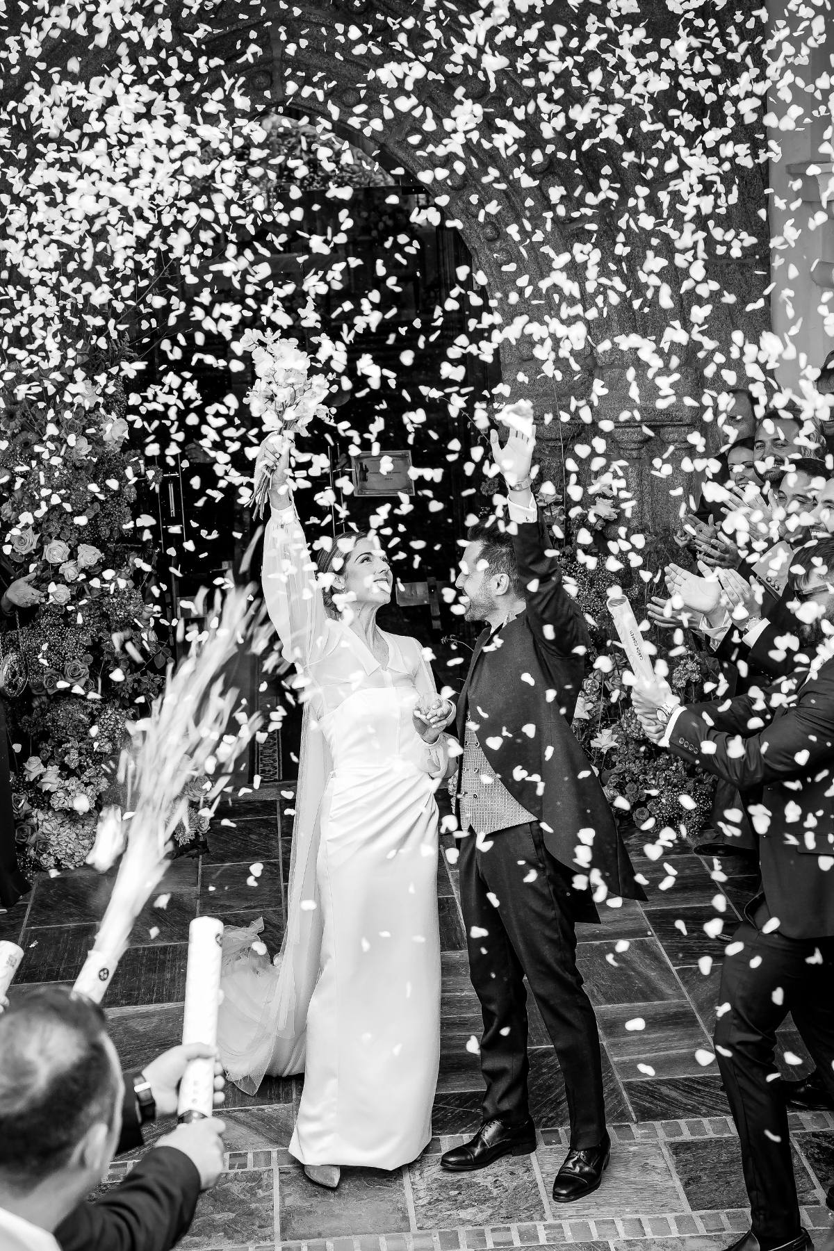Guests showering a laughing couple with petals as they leave the ceremony