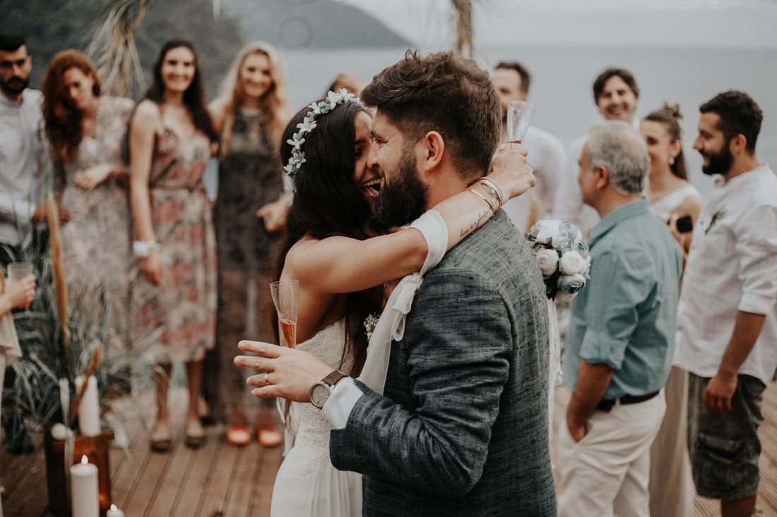 A couple embracing at an outdoor ceremony while their guests stand watching